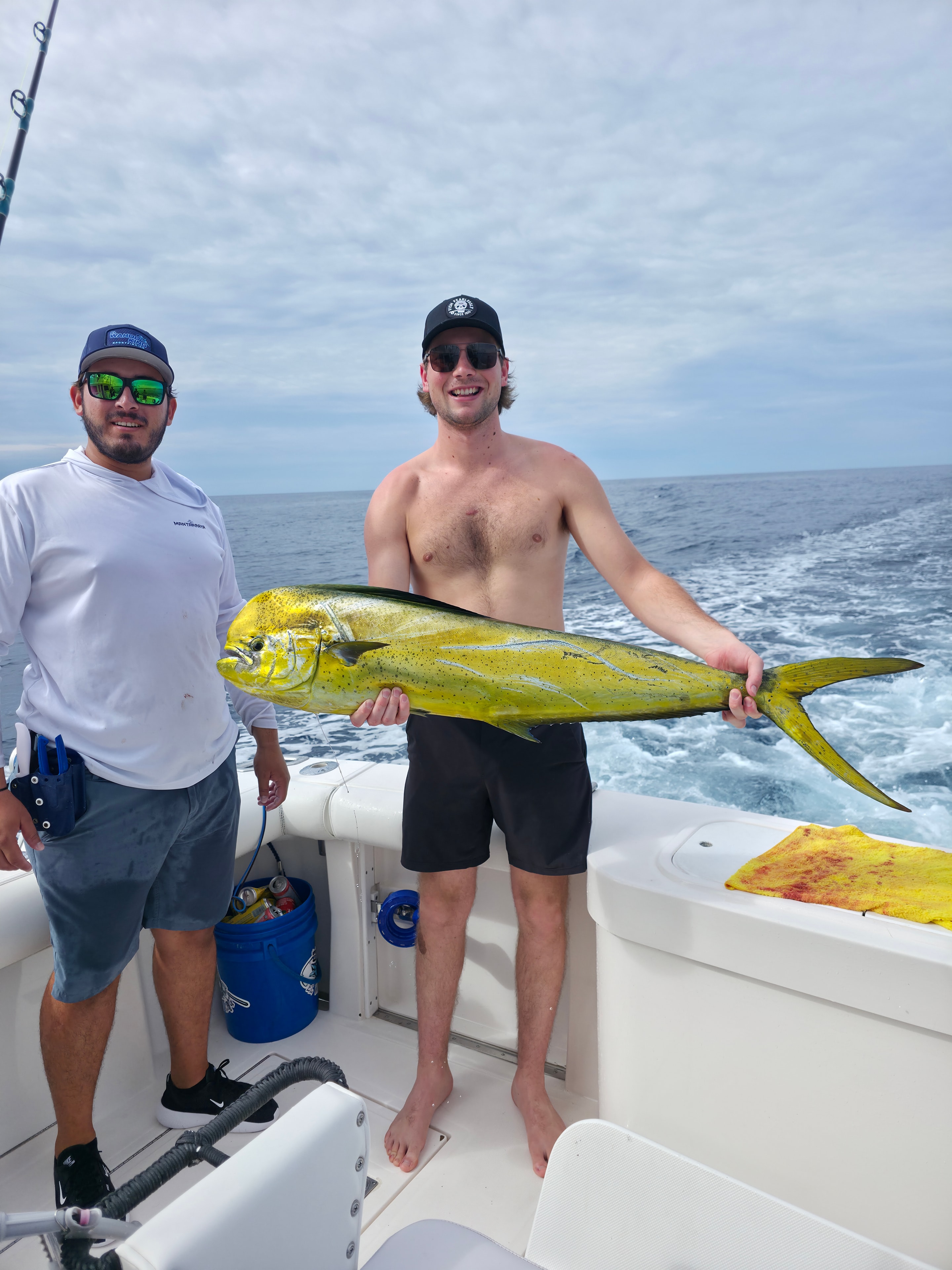 Two anglers holding mahi-mahi on boat