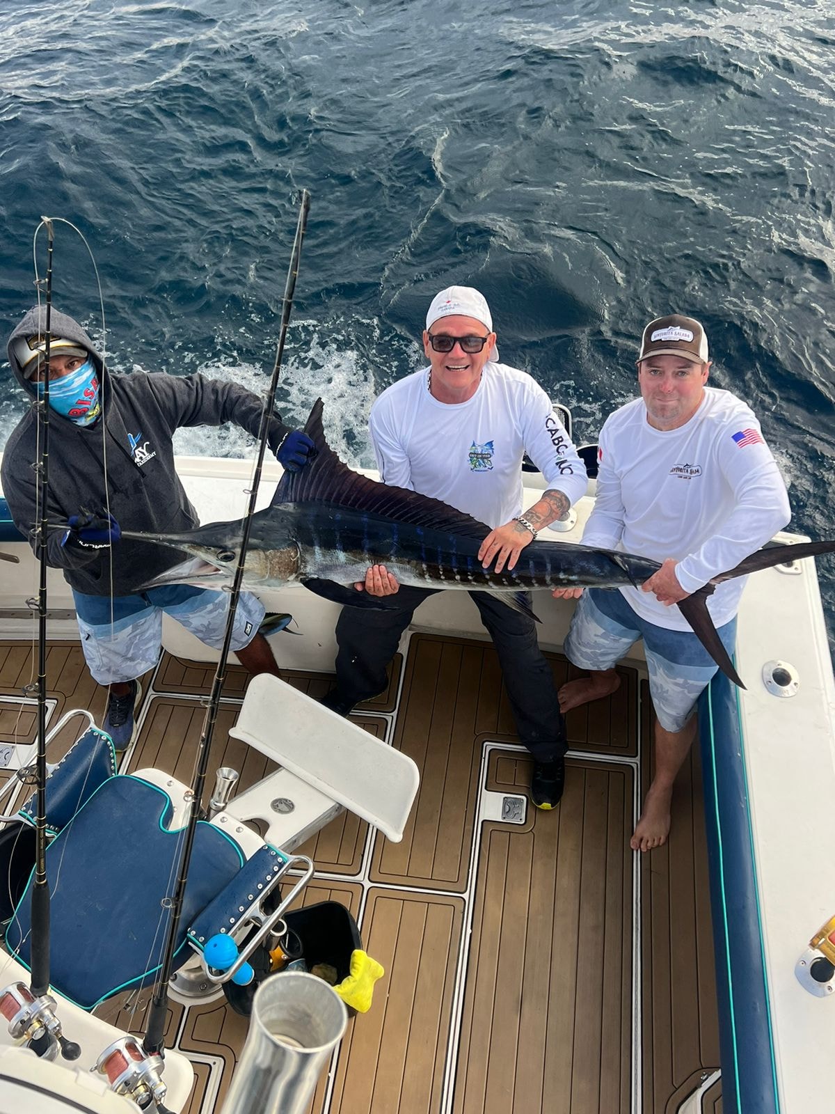 Three anglers with striped marlin on deck